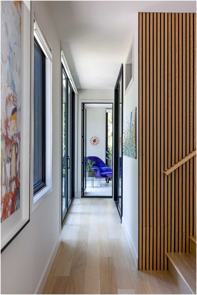 Midcentury modern kitchen hallway with woodslat wall leading into the four seasons room — interior design photography for designers