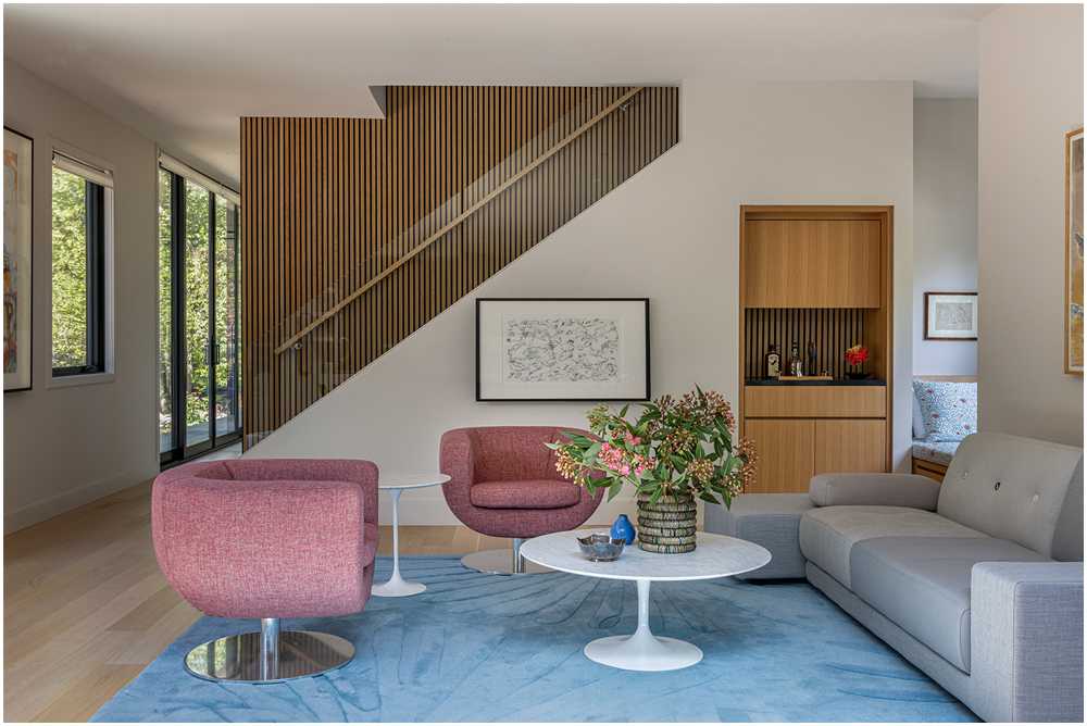 Bright four seasons room with floor-to-ceiling glass walls, terrazzo flooring, midcentury modern furniture, and garden views — interior design photography
